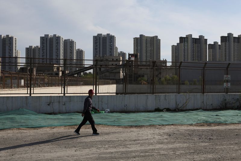 &copy; Reuters. FOTO DE ARCHIVO: Un trabajador pasa por delante de una obra cerca de edificios residenciales en Pekín, China. 14 de abril, 2022. REUTERS/Tingshu Wang/Archivo