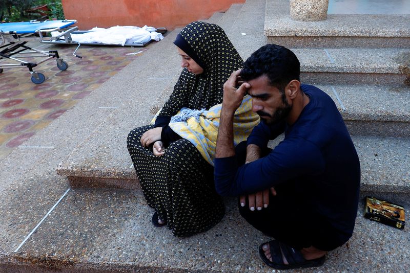 &copy; Reuters. فلسطينيان حزينان بجوار جثث أشخاص قُتلوا في غارات إسرائيلية على مستشفى في خان يونس يوم الخميس. تصوير: محمد سالم - رويترز.