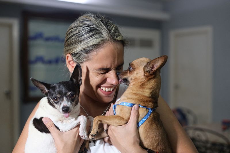 &copy; Reuters. Karolina Vásquez Ramirez brinca com seus cachorros Bingo e Dasha antes de partirem para o aeroporto, em Havana
25/10/2023
REUTERS/Carlos Carrillo