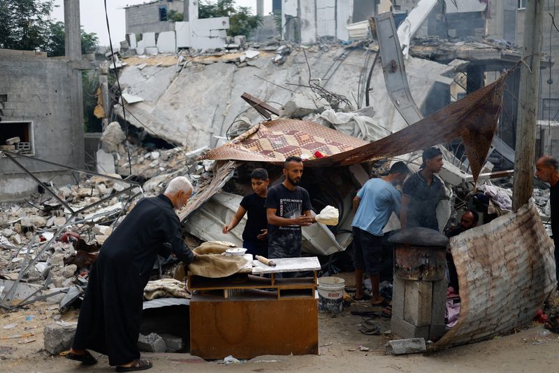 &copy; Reuters. Des Palestiniens préparent de la nourriture à côté des débris causés par des frappes israéliennes dans le sud de Gaza. /Photo prise le 13 novembre 2023/REUTERS/Mohammed Salem 