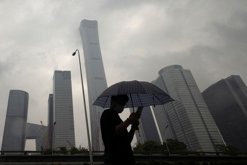 © Reuters. FILE PHOTO: A man walks in the Central Business District on a rainy day, in Beijing, China, July 12, 2023. REUTERS/Thomas Peter/File Photo