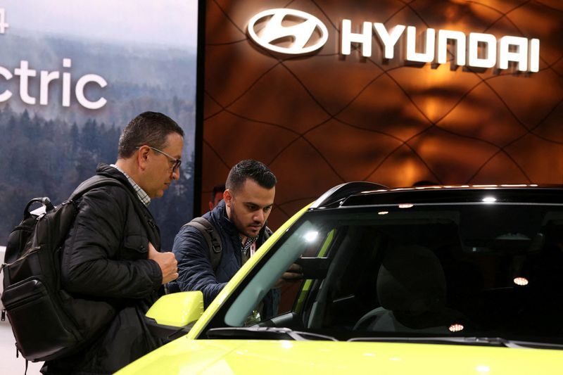 © Reuters. FILE PHOTO: Men stand next to a Hyundai Kona electric vehicle on display at the New York International Auto Show, in Manhattan, New York City, U.S., April 5, 2023. REUTERS/Andrew Kelly/File Photo