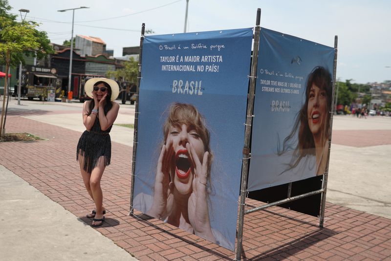 © Reuters. A girl poses next to a photo of singer Taylor Swift, before a concert, following the death of a fan due to the heat during the first day concert, in Rio de Janeiro, Brazil, November 18, 2023. REUTERS/Pilar Olivares