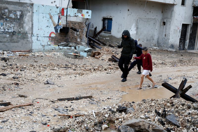 &copy; Reuters. Palestinos caminan mientras llueve, después de que las fuerzas israelíes asaltaron el campo de refugiados de Yenín, en la Cisjordania ocupada por Israel. 19 de noviembre de 2023. REUTERS/Raneen Sawafta