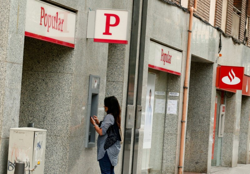 &copy; Reuters. FOTO DE ARCHIVO: Una mujer utiliza un cajero automático del Banco Popular (ATM) junto a una oficina del Santander en Barcelona, España 7 de junio de 2017. REUTERS/Albert Gea/File Photo/File Photo