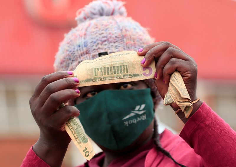 &copy; Reuters. FILE PHOTO: An illegal money changer checks old U.S. dollars at a marketplace in Harare, Zimbabwe, November 26, 2020. REUTERS/Philimon Bulawayo/File Photo