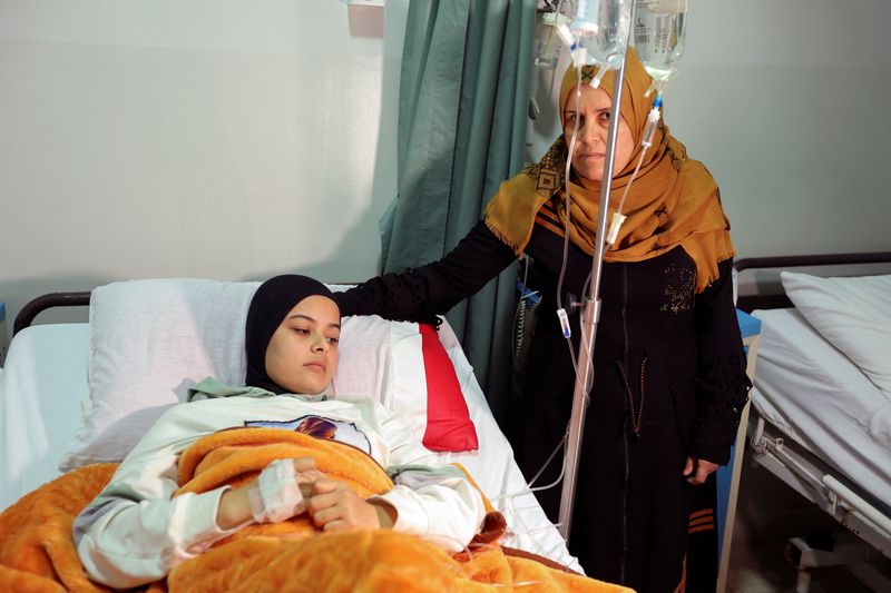 &copy; Reuters. Nahida Mashouz, refugiada siria, junto a su hija Raghad, herida en un bombardeo israelí junto al edificio donde ella y su familia viven en la aldea de Khiam, en un hospital público donde su hija recibe tratamiento, en Marjayoun, sur del Líbano. 13 de n