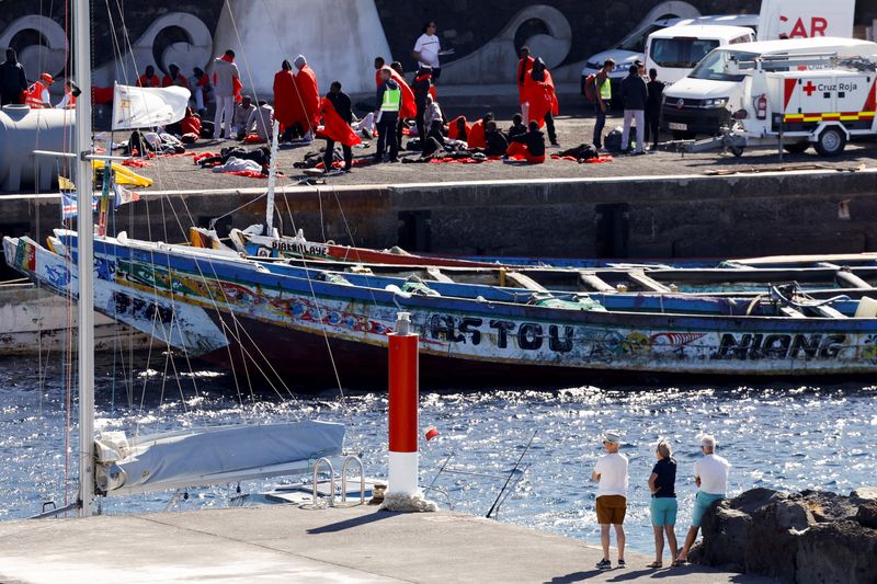 &copy; Reuters. Several tourists observe migrants getting treated as they arrive, at the port of La Restinga, Spain, November 9, 2023. REUTERS/Borja Suarez