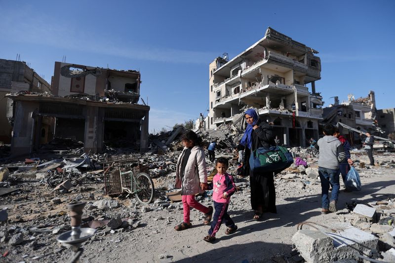 &copy; Reuters. Displaced Palestinians return to their homes as they walk near houses destroyed in an Israeli strike during the conflict, amid the temporary truce between Hamas and Israel, in Khan Younis in the southern Gaza Strip November 24, 2023. REUTERS/Ibraheem Abu 