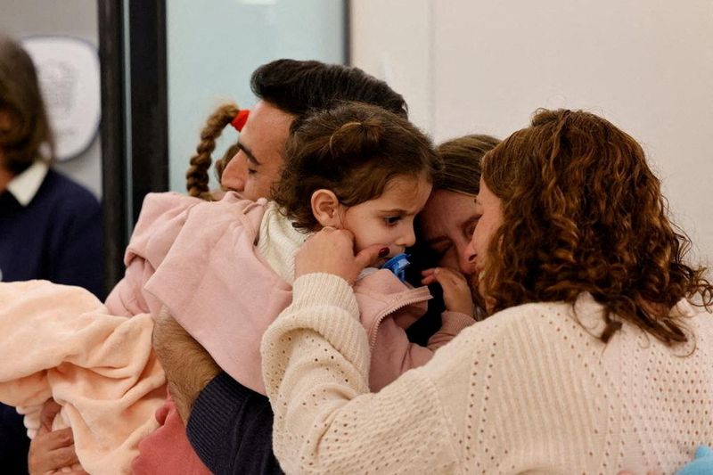 &copy; Reuters. Photo d'Aviv Asher, 2,5 ans, sa sœur Raz Asher, 4,5 ans, et sa mère Doron, réagissent lors de leur rencontre avec Yoni, le père de Raz et Aviv et le mari de Doron, après leur retour en Israël. /Photo prise le 25 novembre 2023 à Petah Tikva, Israël