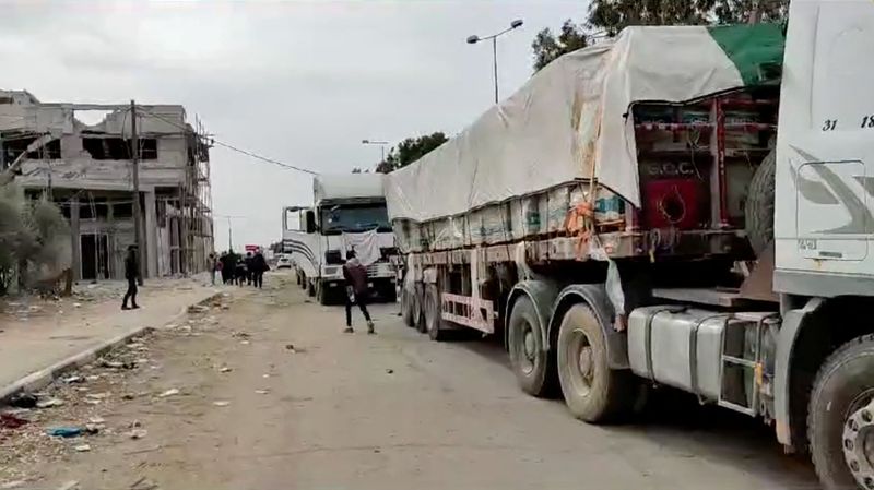 &copy; Reuters. أشخاص يسيرون بجوار شاحنات  تحمل مساعدات إنسانية متجهة إلى شمال غزة وسط اتفاق التبادل بين إسرائيل وحماس في صورة مأخوذة من مقطع فيديو حلصت علي