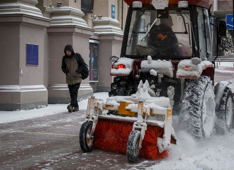 &copy; Reuters. شخص يسير بينما تعمل كاسحة ثلج علي إزالة الثلج من شوارع كييف يوم الاثنين. تصوير : هليب هانيتش - رويترز.