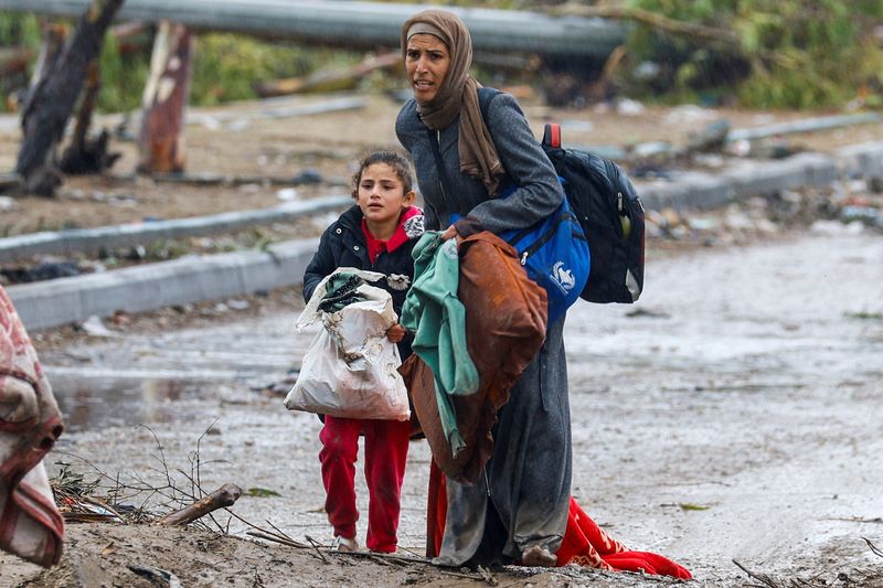&copy; Reuters. Una mujer con su hija camina entre el barro con dirección al norte de la Franja de Gaza. 27 noviembre 2023. REUTERS/Ibraheem Abu Mustafa