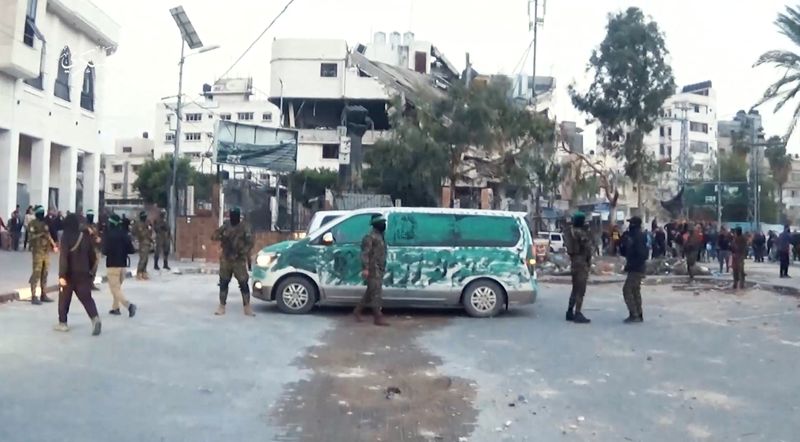 &copy; Reuters. مسلحون من حركة حماس يقفون إلى جانب مركبات فيما يسلمون رهائن اختطفوا في هجوم السابع من أكتوبر تشرين الأول على إسرائيل إلى مسؤولين باللجنة ال