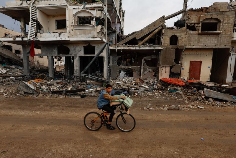 © Reuters. طفل فلسطيني يقود دراجة إلى جانب ركام منزل تعرض لقصف إسرائيلي خلال الصراع وسط هدنة مؤقتة بين حركة حماس وإسرائيل في مدينة خان يونس في جنوب قطاع غزة يوم الاثنين. تصوير: محمد سالم - رويترز.