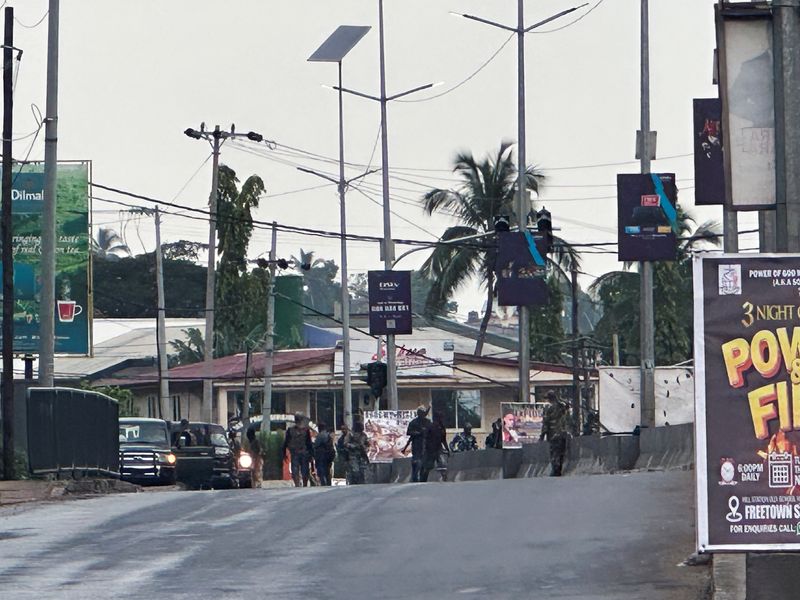 &copy; Reuters. Des hommes armés cagoulés en treillis militaire se tiennent dans une rue après que des hommes armés non identifiés aient attaqué une caserne militaire et tenté de pénétrer dans une armurerie au rond-point de Congo Cross à Freetown, Sierra Leone.