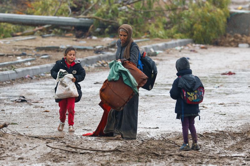 &copy; Reuters. امرأة فلسطينية فرت من شمال غزة تساعد طفليها في حمل أمتعتهم فيما يتوجهون نحو الجنوب خلال هدنة مؤقتة بين حركة حماس وإسرائيل بالقرب من مدينة غز