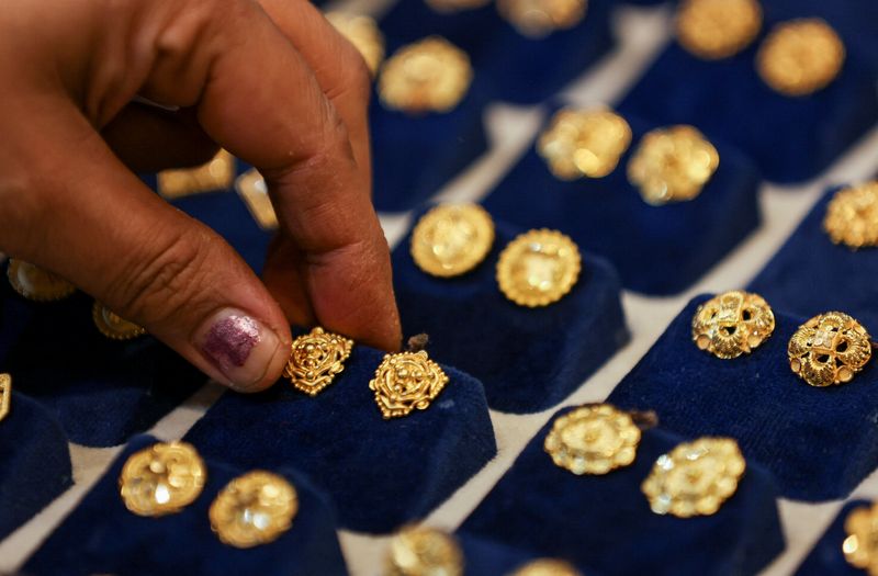 © Reuters. FILE PHOTO: A woman picks a gold earring at a jewellery shop in the old quarters of Delhi, India, May 24, 2023. REUTERS/Anushree Fadnavis