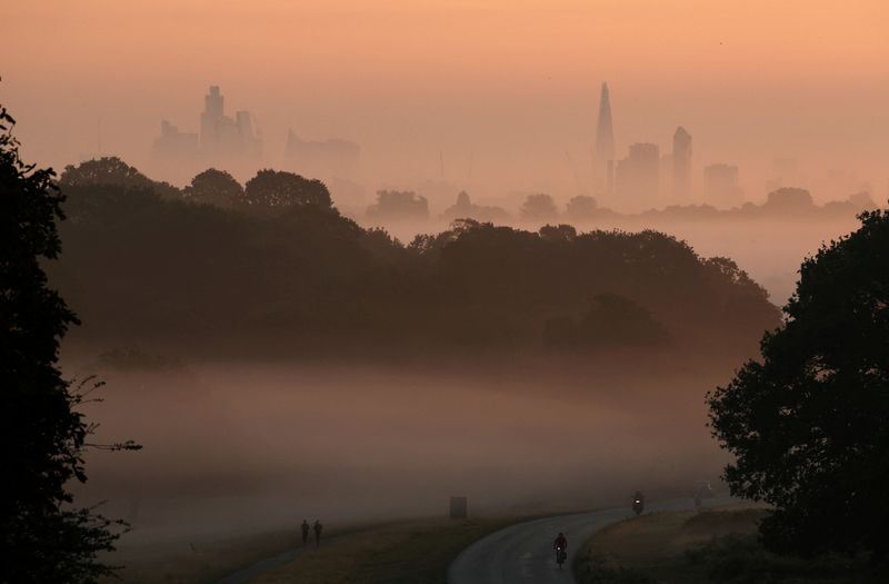 © Reuters. FILE PHOTO: Cyclists ride through fog at sunrise with the London skyline seen behind, in Richmond Park, London, Britain, September 15, 2023. REUTERS/Toby Melville/File Photo