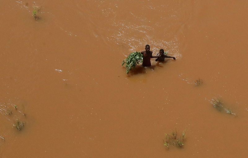 &copy; Reuters. FOTO DE ARCHIVO: Un grupo de personas se aferra a unas plantas mientras vadean las aguas de las inundaciones tras ser desplazadas por las fuertes lluvias en Garsen, en el delta del Tana, en el condado del río Tana, Kenia. 23 de noviembre, 2023. REUTERS/T