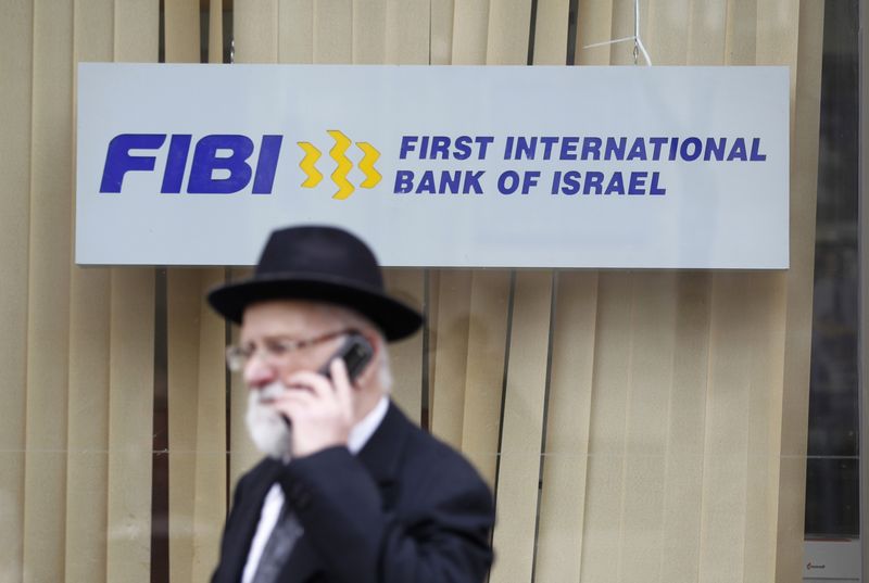 &copy; Reuters. FILE PHOTO: A man speaks on his mobile phone as he walks in front of a First International Bank of Israel branch in Jerusalem January 27, 2014. REUTERS/Baz Ratner 