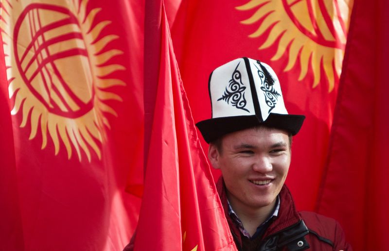 &copy; Reuters. FOTO DE ARCHIVO. Un hombre con un sombrero nacional kirguís posa con banderas nacionales antes de un mitin para conmemorar el Día de la Bandera y el Día de Kolpak en Bishkek, Kirguistán. 4 de marzo de 2013. REUTERS/Shamil Zhumatov