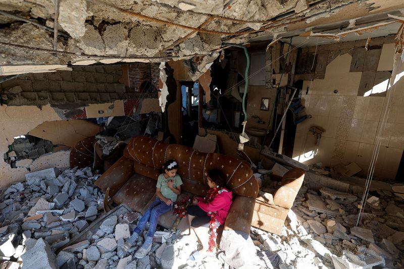 © Reuters. Palestinian girls sit on a couch at the remains of their house hit in Israeli strikes during the conflict,  amid the temporary truce between Israel and the Palestinian Islamist group Hamas, in Khan Younis, in the southern Gaza Strip, November 29, 2023. REUTERS/Mohammed Salem