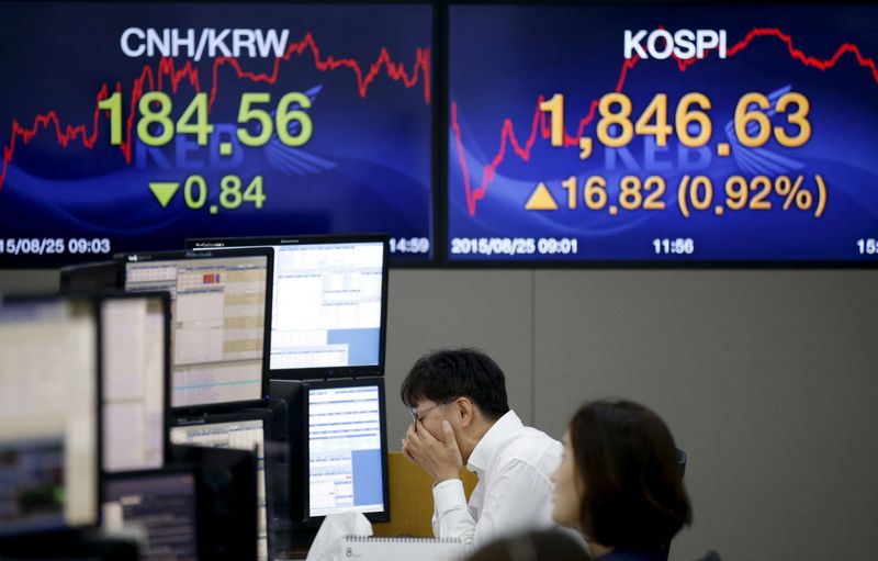 &copy; Reuters. FILE PHOTO: A currency dealer works in front of electronic boards showing the Korea Composite Stock Price Index (KOSPI) (R), and the exchange rates between the Chinese yuan and South Korean won (L), at a dealing room of a bank in Seoul, South Korea, Augus