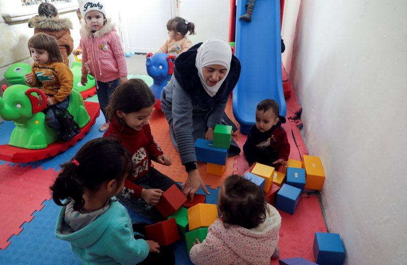 © Reuters. Safaa Kamel, 35, a teacher who says she suffered health effects following a gas attack on her home region of Eastern Ghouta in Syria in 2013 and, now displaced to the northwestern Syrian region of Afrin, plays with children at a school in the northern Syrian town of Afrin, Syria November 28, 2023. REUTERS/Mahmoud Hassano