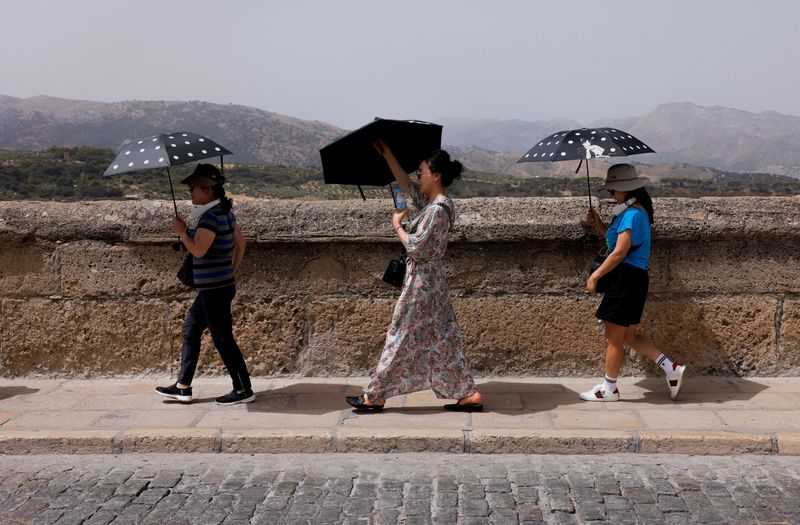 &copy; Reuters. Turistas de Corea del Sur se protegen del fuerte sol con sombrillas durante la tercera ola de calor del verano en España, en Ronda, España, 9 de agosto de 2023. REUTERS/Jon Nazca/Foto de archivo