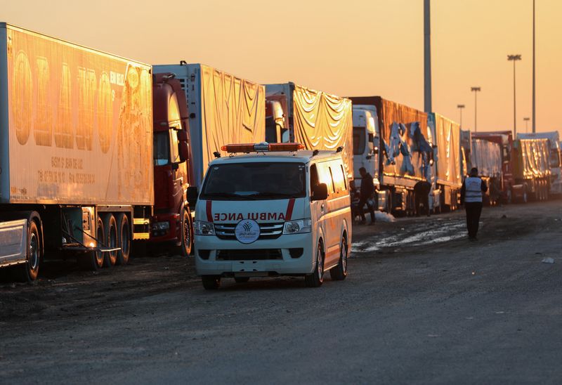 &copy; Reuters. Las personas caminan junto a camiones en fila cerca del cruce fronterizo de Rafah en Egipto para ingresar a la Franja de Gaza. Noviembre 30, 2023. REUTERS/Mohamed Abd El Ghany