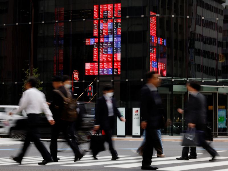 &copy; Reuters. FILE PHOTO: Pedestrians walk past an electronic board displaying various companies' share prices, at a business district in Tokyo, Japan, October 31, 2023. REUTERS/Kim Kyung-Hoon/File Photo