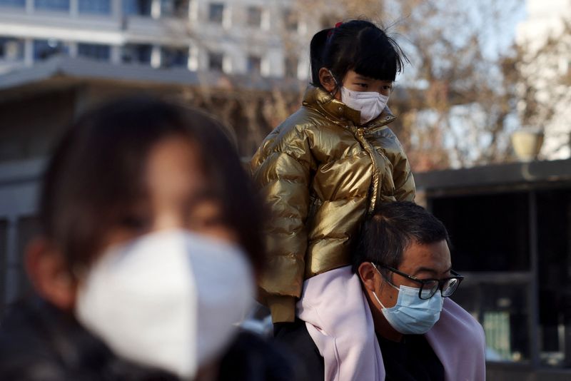 &copy; Reuters. Un homme porte un enfant sur ses épaules devant un hôpital pour enfants à Pékin, en Chine. /Photo prise le 24 novembre 2023/REUTERS/Florence Lo