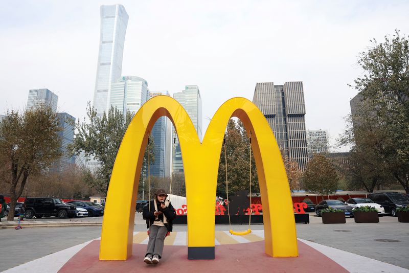&copy; Reuters. A woman sits on a swing attached to a giant sign of McDonald's, outside its themed exhibition in Beijing, China December 4, 2023. REUTERS/Tingshu Wang