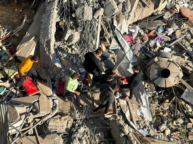 © Reuters. فلسطينيون يتجمعون داخل موقع تعرض لضربات إسرائيلية في رفح جنوب قطاع غزة يوم الأحد . تصوير : فادي شانة - رويترز .  