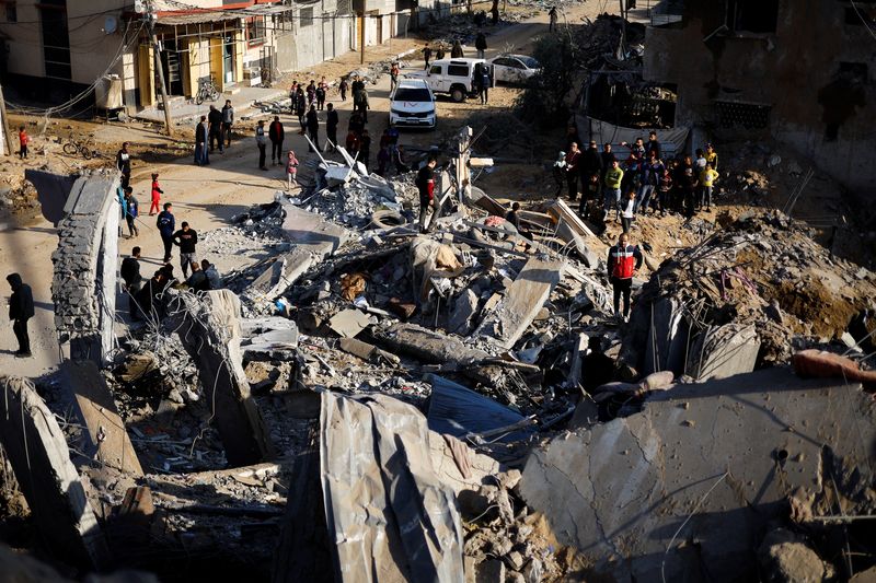 © Reuters. فلسطينيون يتفقدون منزلا دُمر في قصف إسرائيلي في مدينة رفح بجنوب قطاع غزة يوم الاثنين. تصوير: محمد سالم - رويترز.