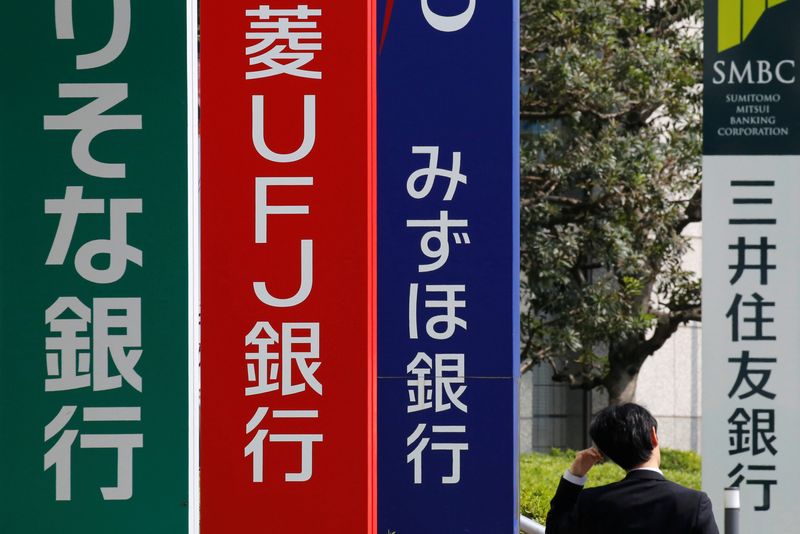 &copy; Reuters. FILE PHOTO: A man walks past signboards of Sumitomo Mitsui Banking Corporation (R), Mizuho Bank (3rd L), MUFG Bank (2nd L), and Resona Bank in Tokyo, Japan April 3, 2018. REUTERS/Toru Hanai