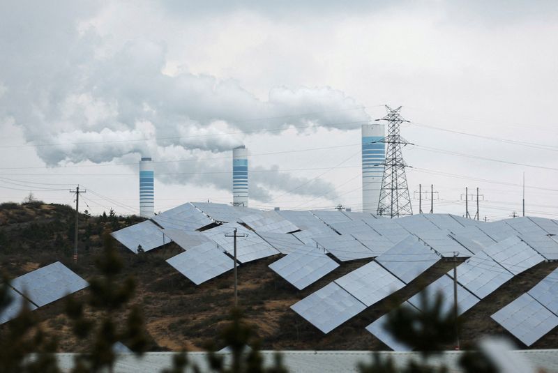 © Reuters. FILE PHOTO: Smoke rises from chimneys near solar panels, during a Huawei-organised media tour, in Shaanxi province, China April 24, 2023. REUTERS/Tingshu Wang/File Photo