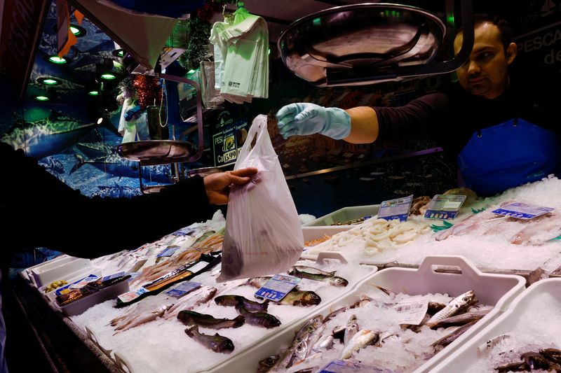 &copy; Reuters. Un poissonnier tend un sac à un client dans un supermarché à Madrid. /Photo prise le 27 décembre 2022/REUTERS/Violeta Santos Moura 
