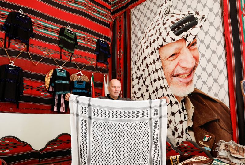 &copy; Reuters. عزت حرباوي يعرض كوفية في محل للمنسوجات في الخليل بالضفة الغربية المحتلة يوم 24 يناير كانون الثاني 2023. تصوير: موسي قواسمه - رويترز.