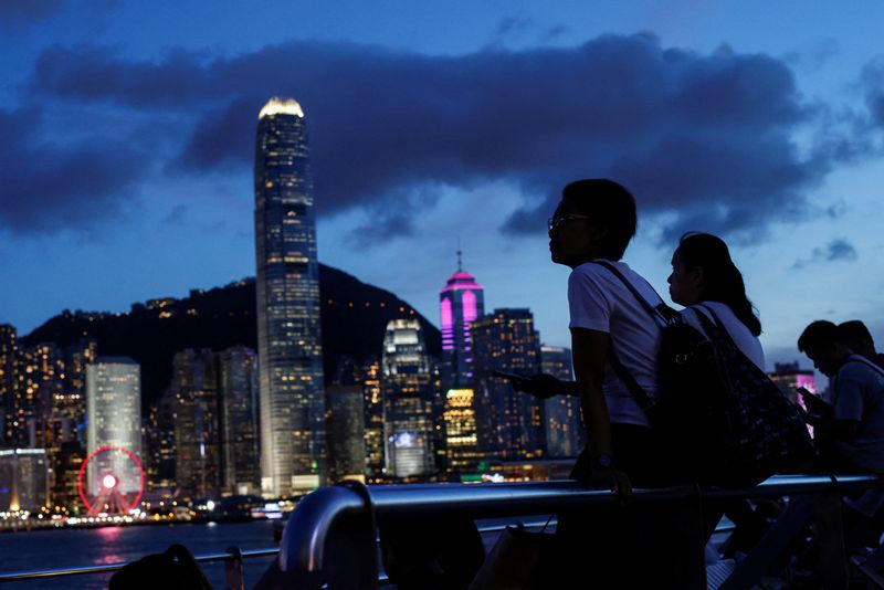 &copy; Reuters. Tourists relax on the waterfront in front of Victoria Harbour, with the iconic skyline buildings as a backdrop, in Hong Kong, China June 28, 2023. REUTERS/Tyrone Siu/File Photo