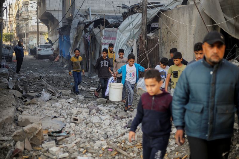 &copy; Reuters. Niños palestinos llevan objetos mientras caminan en el lugar de los ataques israelíes, en medio del conflicto en curso entre Israel y el grupo islamista palestino Hamás, en Jan Yunis, en el sur de la Franja de Gaza. 6 de diciembre de 2023. REUTERS/Ahme