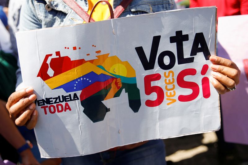 &copy; Reuters. FOTO DE ARCHIVO: Una partidaria del gobierno sostiene un cartel en el que se lee: "Venezuela Toda, vota 5 veces Sí" mientras participa en un evento para recoger firmas en apoyo a un referéndum sobre los derechos de Venezuela a la región potencialmente 