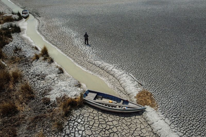 &copy; Reuters. Un hombre caminando sobre un área seca que muestra la caída en el nivel del lago Titicaca, la cuenca de agua dulce más grande de América Latina, a medida que se acerca a niveles récord, en la isla Cojata, Bolivia. 26 de octubre de 2023. REUTERS/Claud