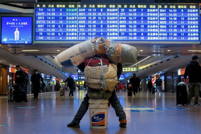 © Reuters. FILE PHOTO: A traveller is seen with his belongings at a railway station, following the coronavirus disease (COVID-19) outbreak, in Beijing, China January 13, 2021. Picture taken January 13, 2021. REUTERS/Thomas Peter/File Photo