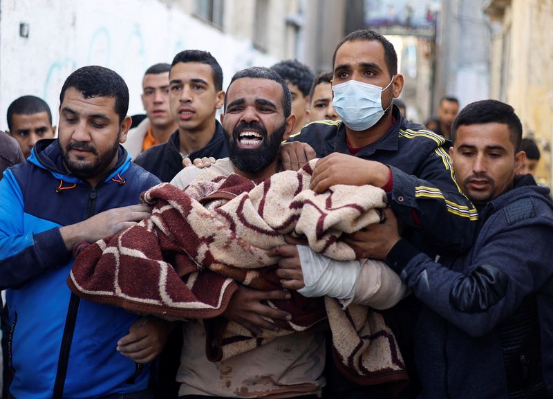 &copy; Reuters. Un palestino carga con un niño herido en el lugar de los ataques israelíes contra casas en Ráfah, en el marco del actual conflicto entre Israel y el grupo islamista palestino Hamás, en Ráfah, en el sur de la Franja de Gaza, 7 de diciembre de 2023. RE