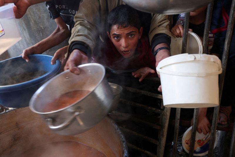 &copy; Reuters. FOTO DE ARCHIVO: Un niño palestino reacciona, mientras la gente se reúne para recibir su parte de comida caritativa ofrecida por voluntarios, en medio de la escasez de alimentos, mientras continúa el conflicto entre Israel y el grupo islamista palestin