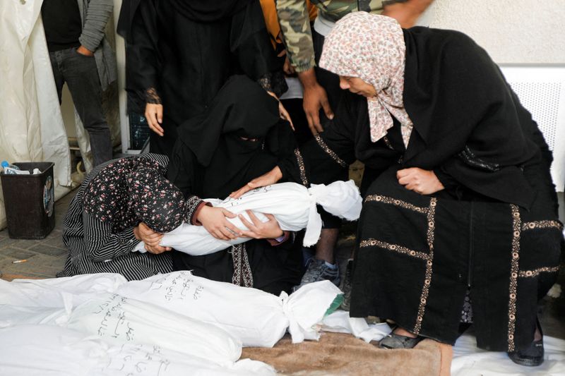 © Reuters. Mujeres palestinas lloran sosteniendo el cuerpo de un niño muerto en ataques israelíes contra casas, en el hospital Abu Yousef al-Najjar en Rafah, en el sur de la Franja de Gaza. 7 de diciembre de 2023. REUTERS/Saleh Salem