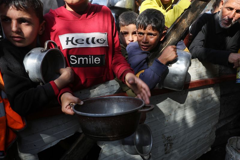 &copy; Reuters. أطفال فلسطينيون ينتظرون الحصول على نصيبهم من الطعام الذي يقدمه لهم متطوعون في رفح بجنوب قطاع غزة في الثاني من ديسمبر كانون الأول 2023 وسط أزمة