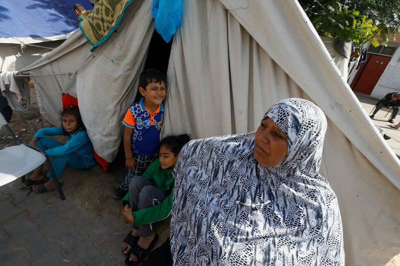 &copy; Reuters. سيدة فلسطينية تقف مع أطفالها يوم الخميس خارج خيمة بمدرسة في رفح جنوب قطاع غزة لإيواء النازحين الذين فروا من منازلهم بسبب القصف الإسرائيلي . 